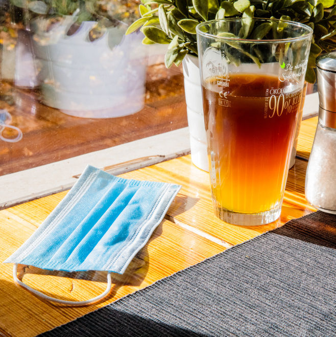 Neue Corona-Hilfen für temporäre Schließungen im November (im Bild: ein Mund-Nasen-Schutz auf einem Tisch neben einem Getränk).